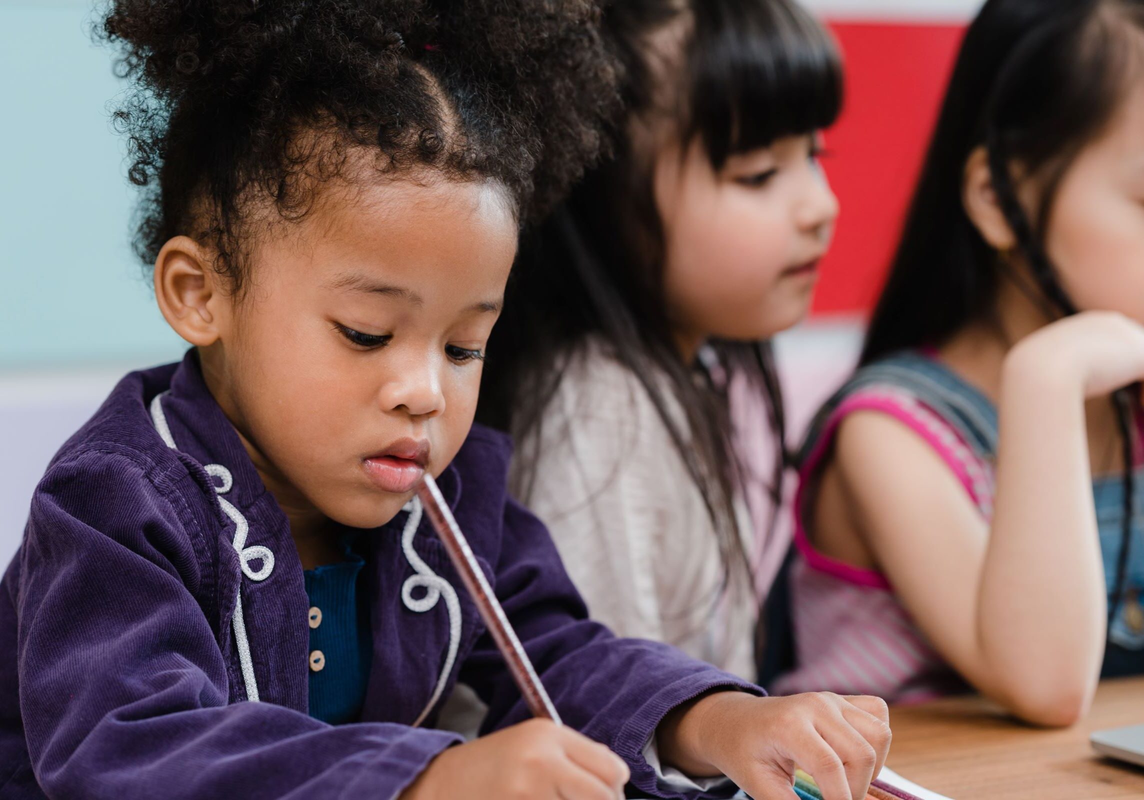 Preschool students practicing fine motor skills and early literacy through a focused writing activity