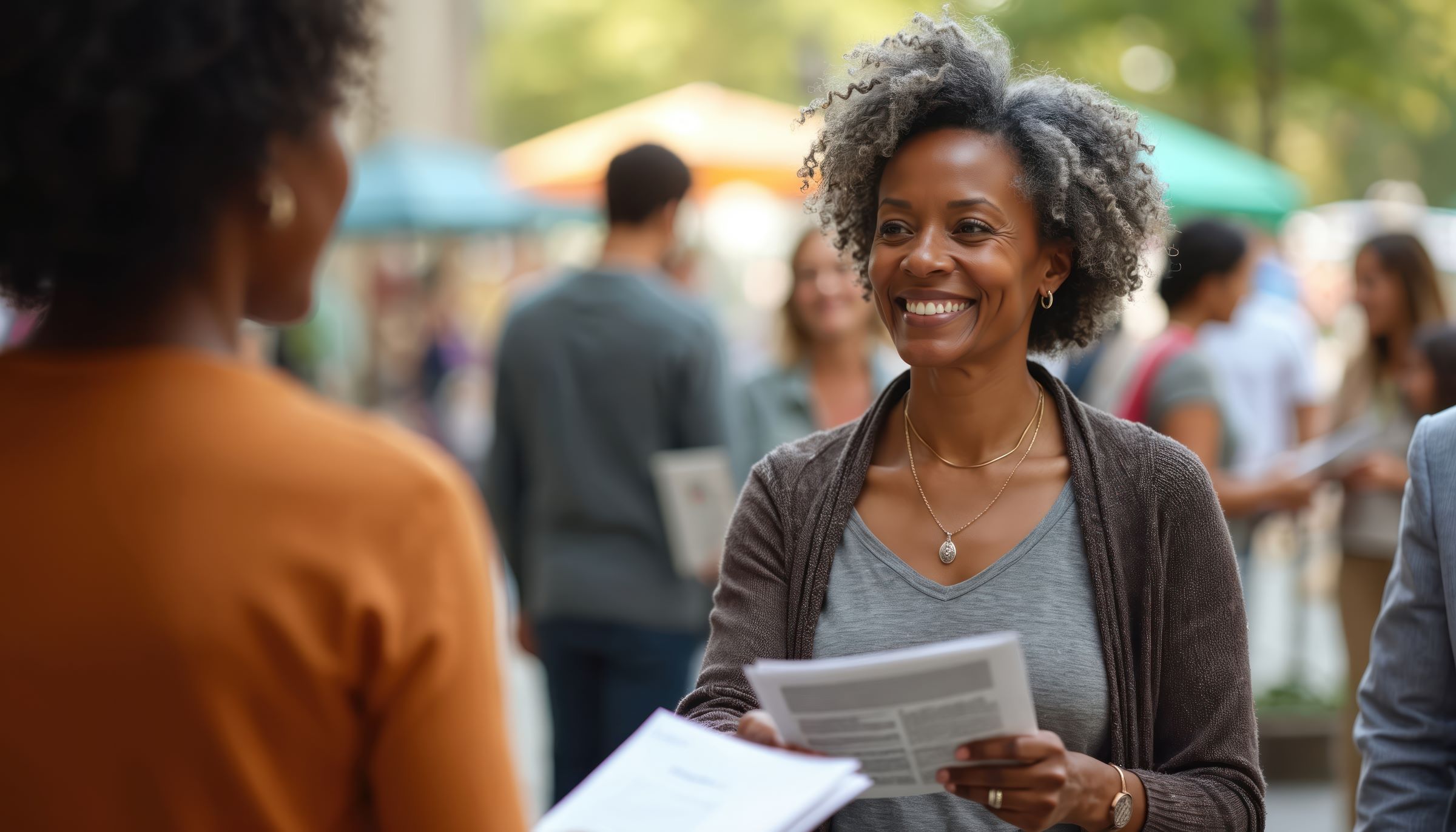 A staff member or volunteer providing information and support to a community member during an outdoor event.
