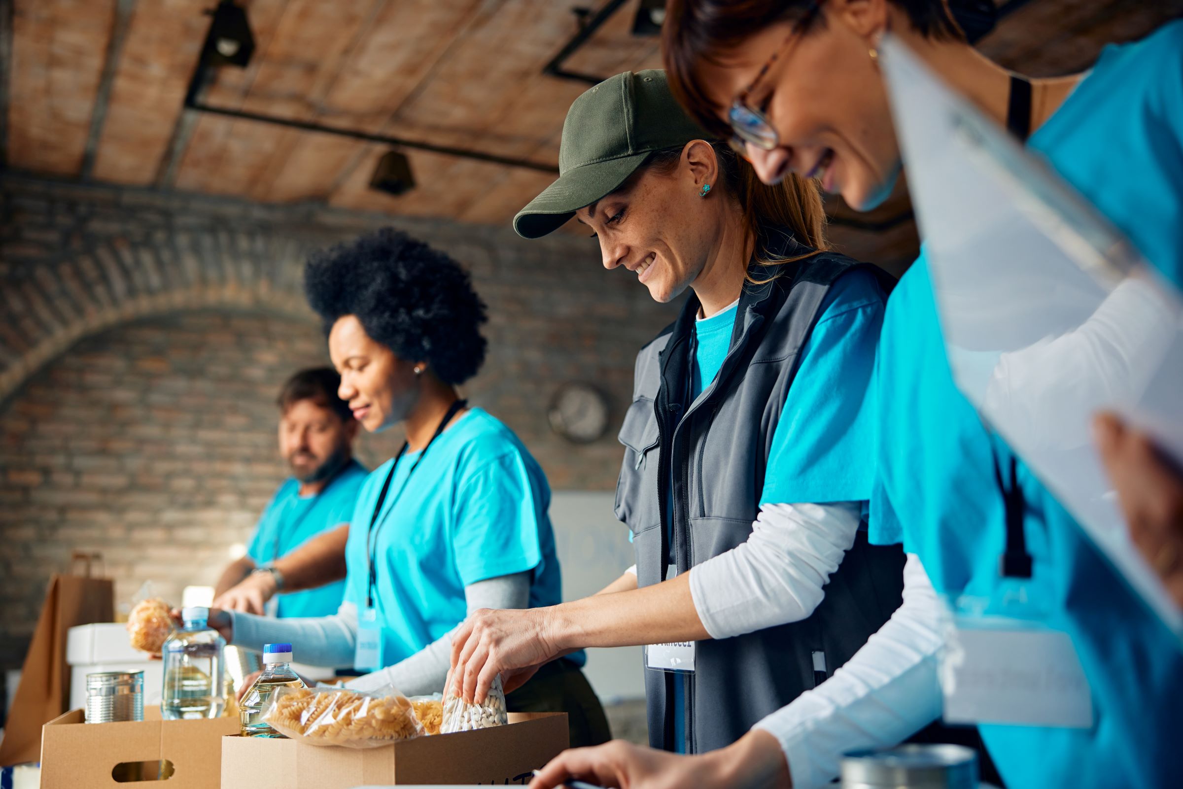 A group of volunteers assembling food packages with canned goods and supplies indoors.
