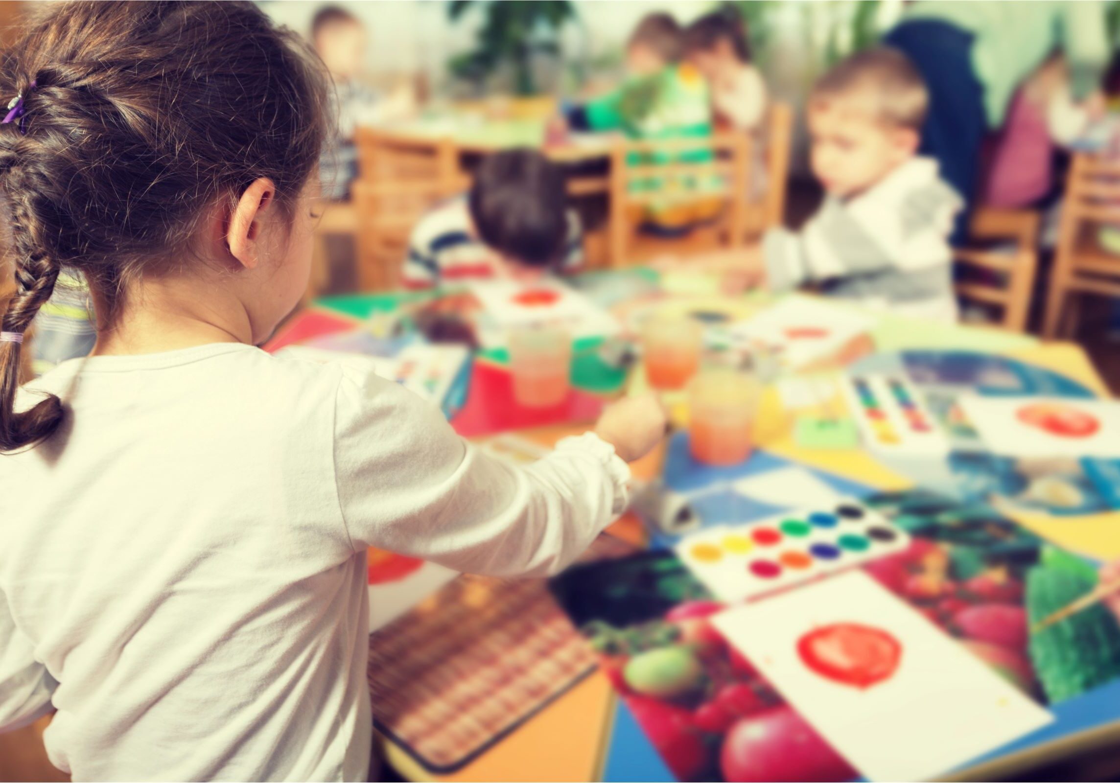 A preschool student developing fine motor skills and creativity through a guided watercolor painting activity.