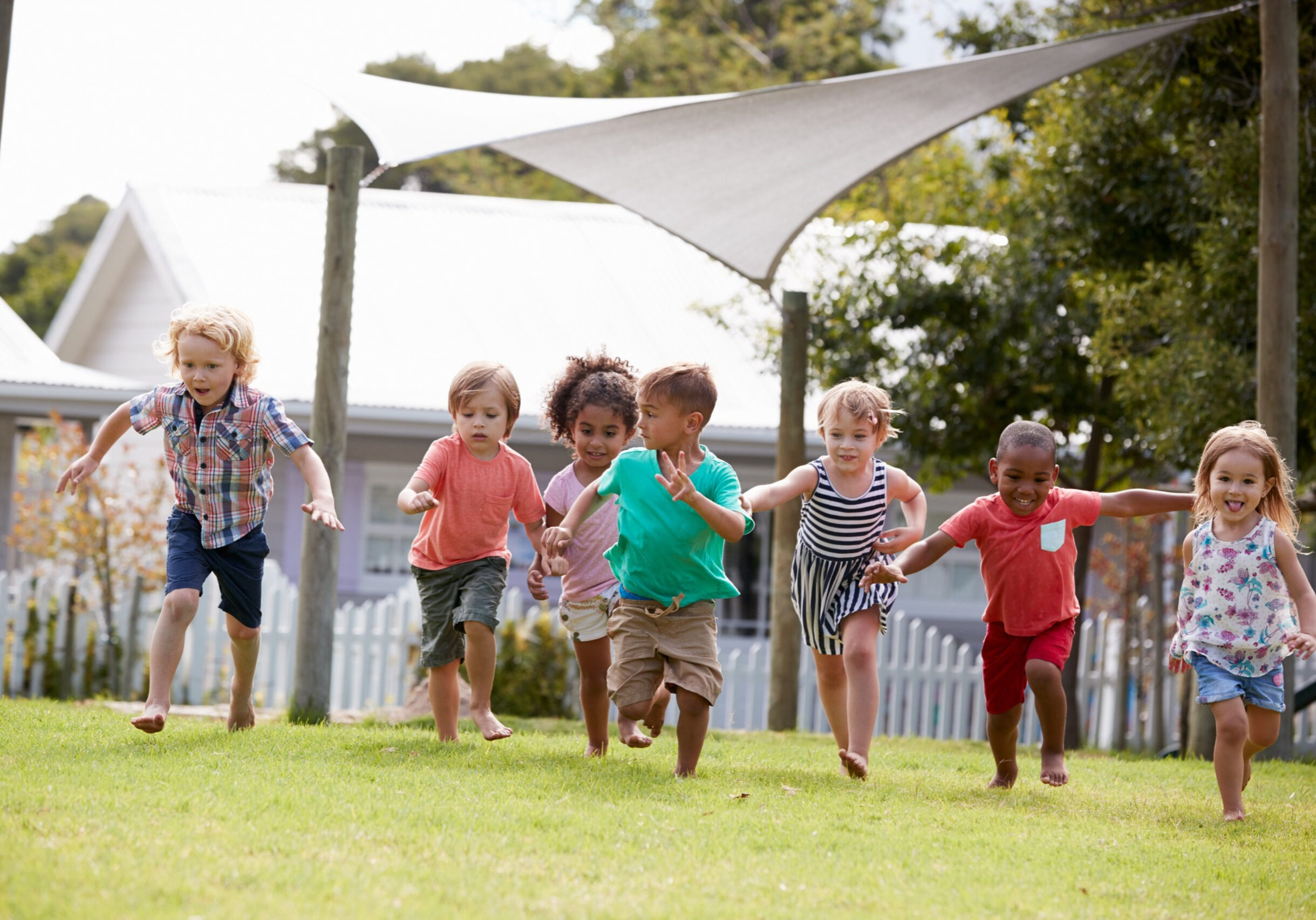 Children running and playing together on a grassy playground outdoors.