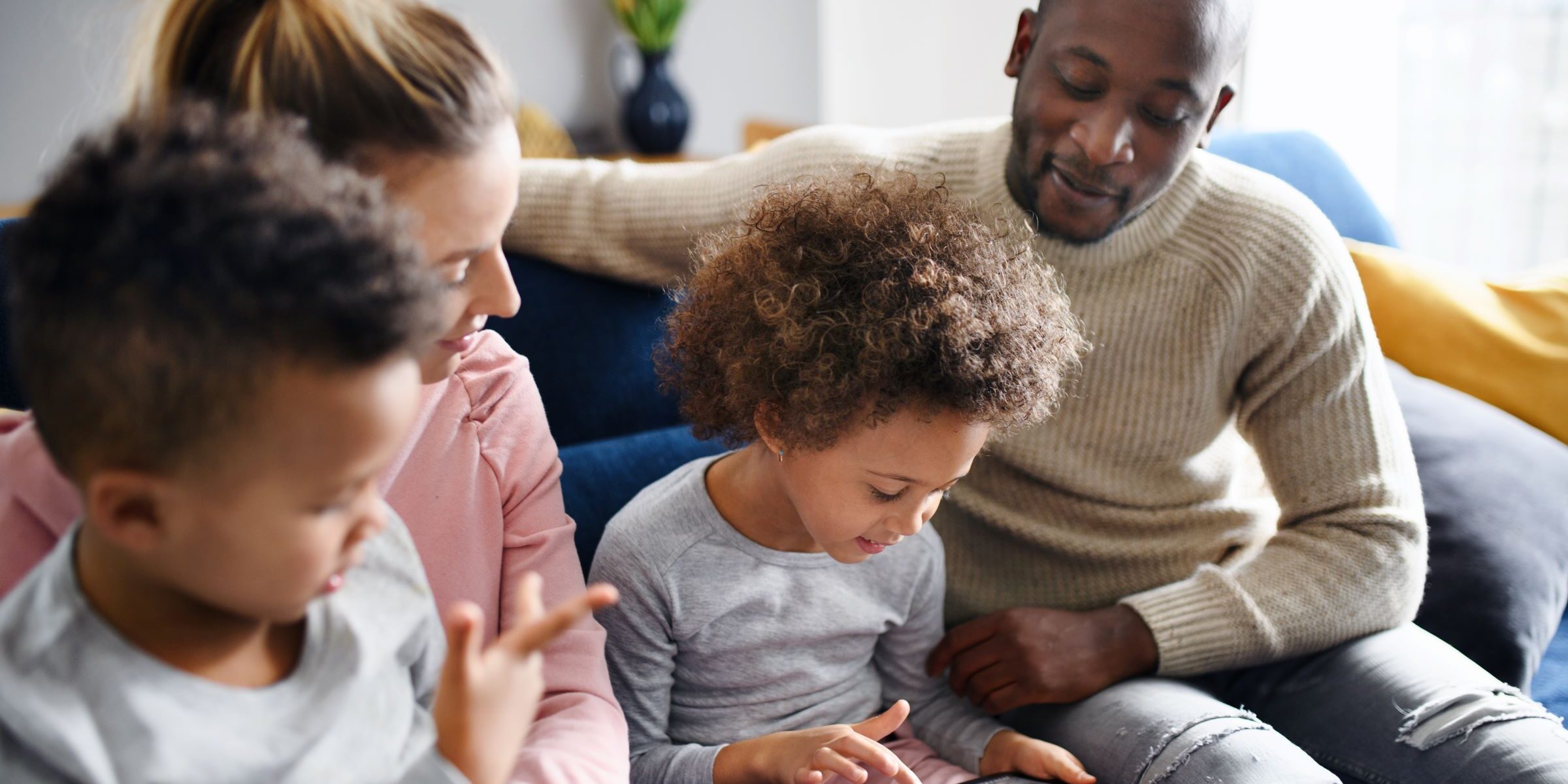 Parents and children engaging in a digital literacy activity together at home.